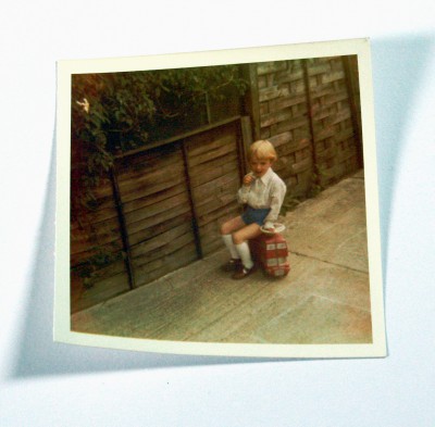 Polaroid photo of child sitting on a toy london bus