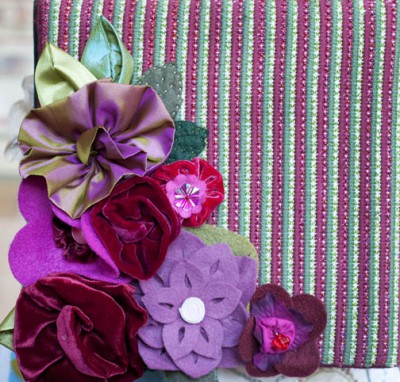 Fabric purple flowers decorating a corner of a cross stitch square